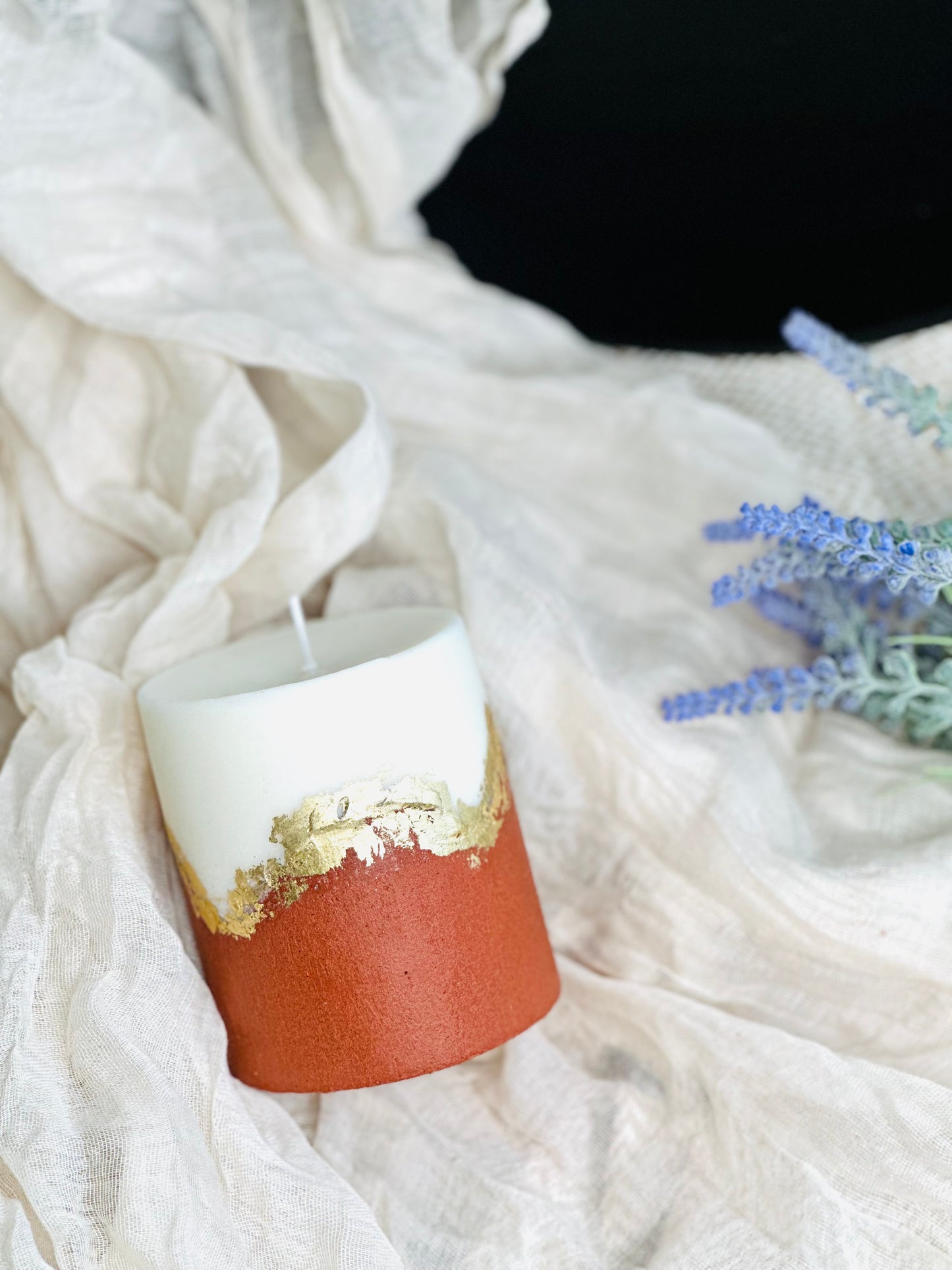 Decorative candle with gold accents on a white textured surface made in UK