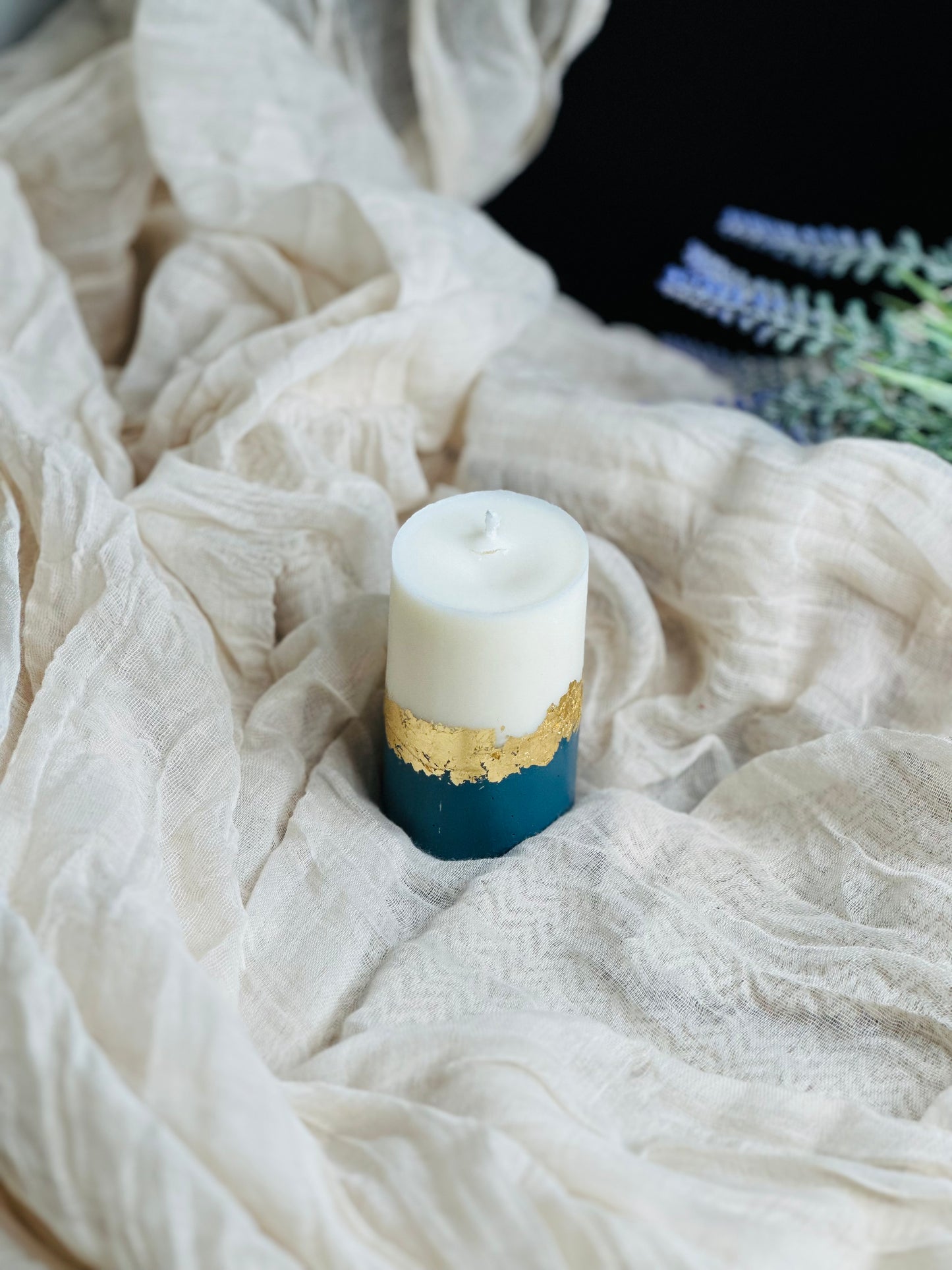 Candle with gold and blue base on a textured white fabric background - UK made