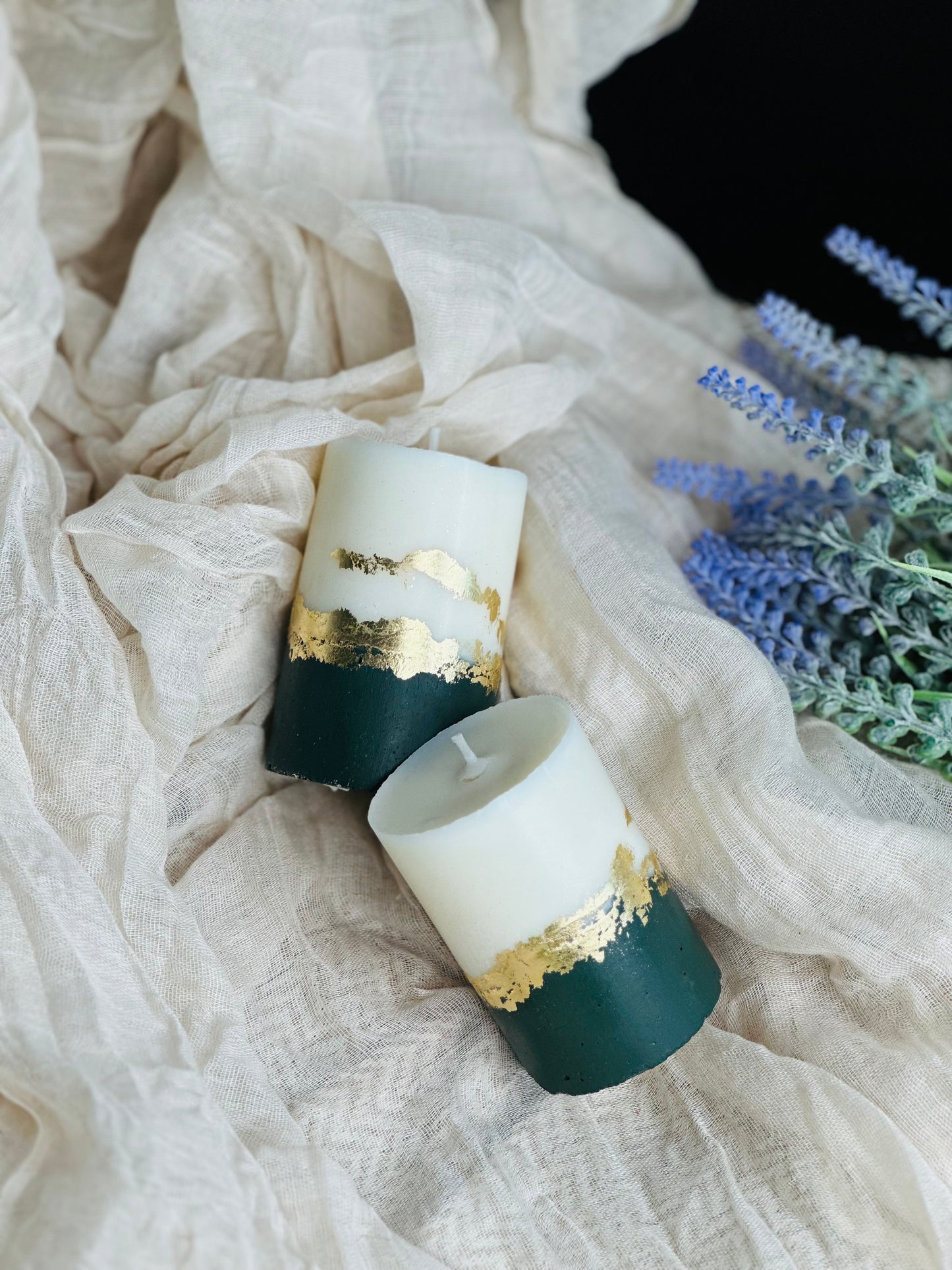 Two candles with gold accents on a textured fabric background with lavender flowers - UK made