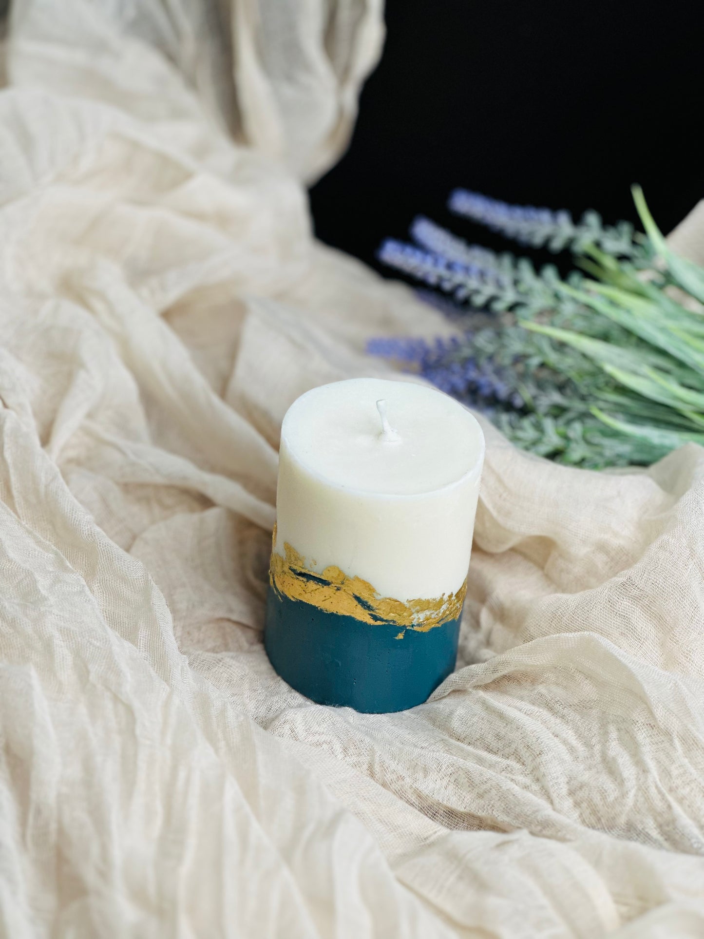 Candle with gold accent on a white fabric background