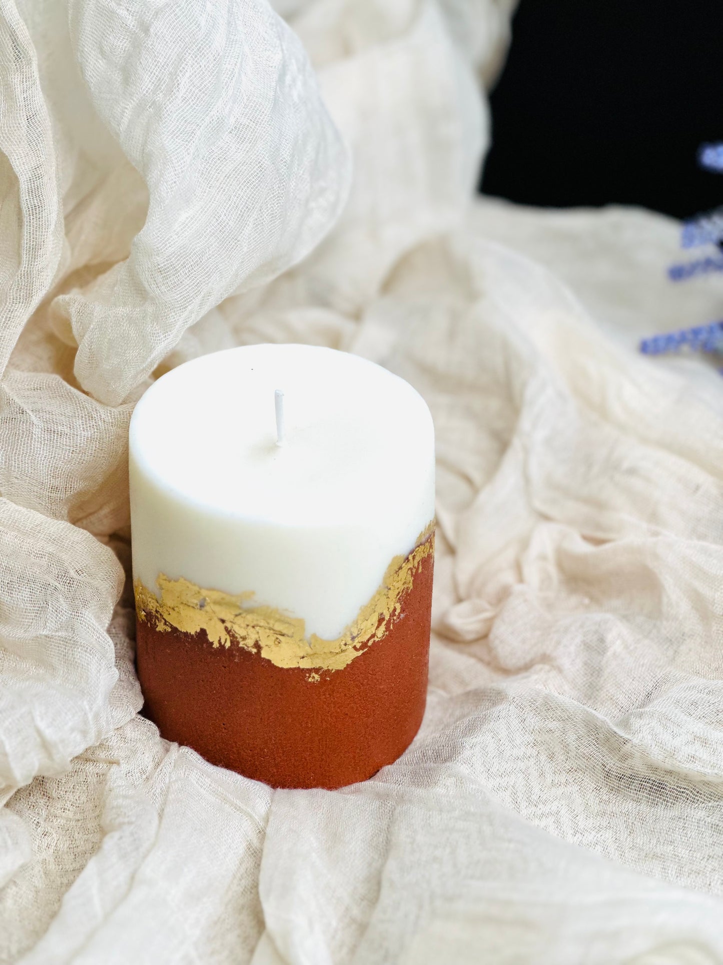 Candle with gold accent on a white fabric background made in UK