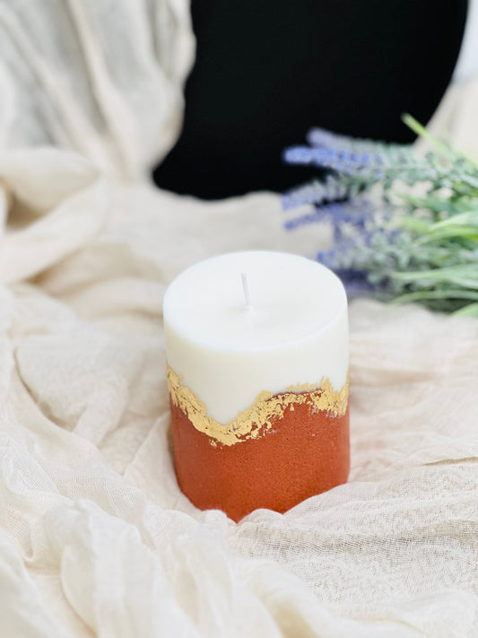 Candle with gold accent on a textured surface with blurred background made in UK
