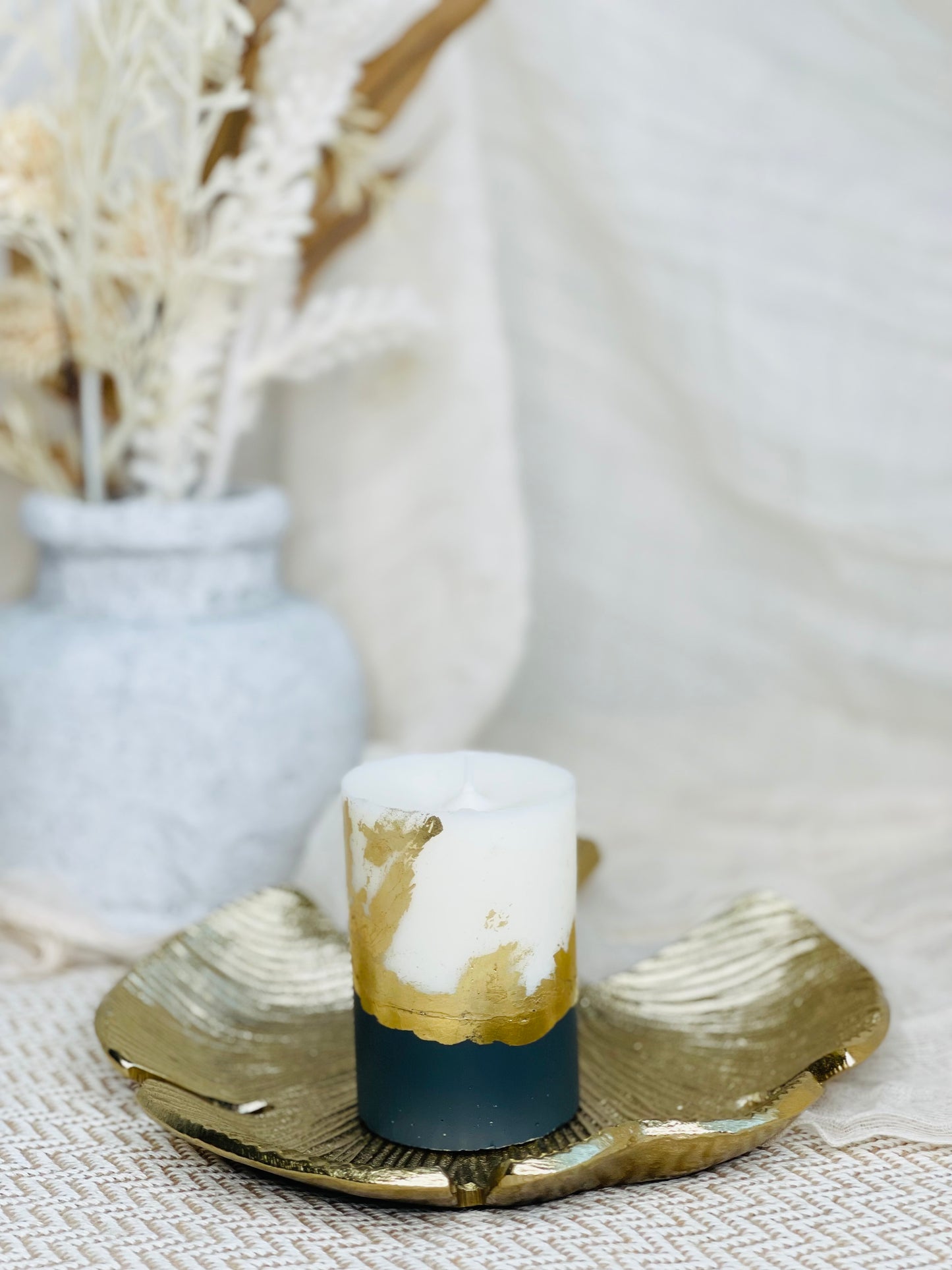 Decorative candle with gold and navy design on a textured surface with a blurred background made in UK