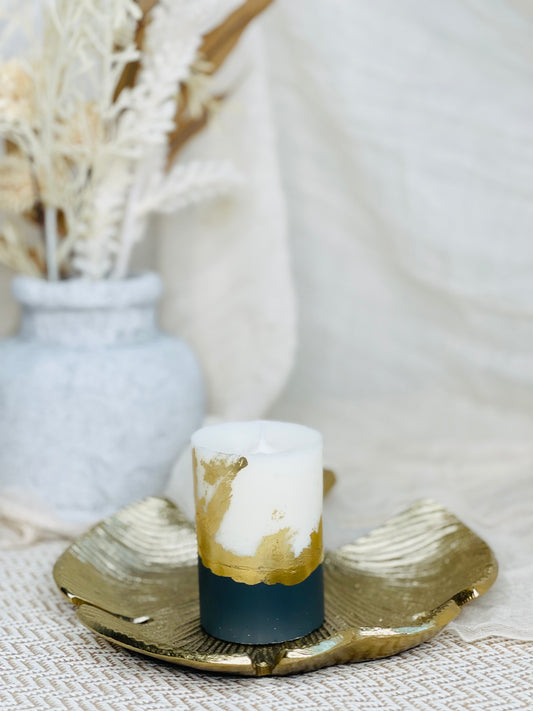 Decorative candle with gold and navy design on a textured surface with a blurred background made in UK