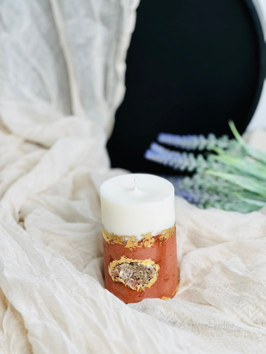 Decorative candle with gold accents on a textured white surface