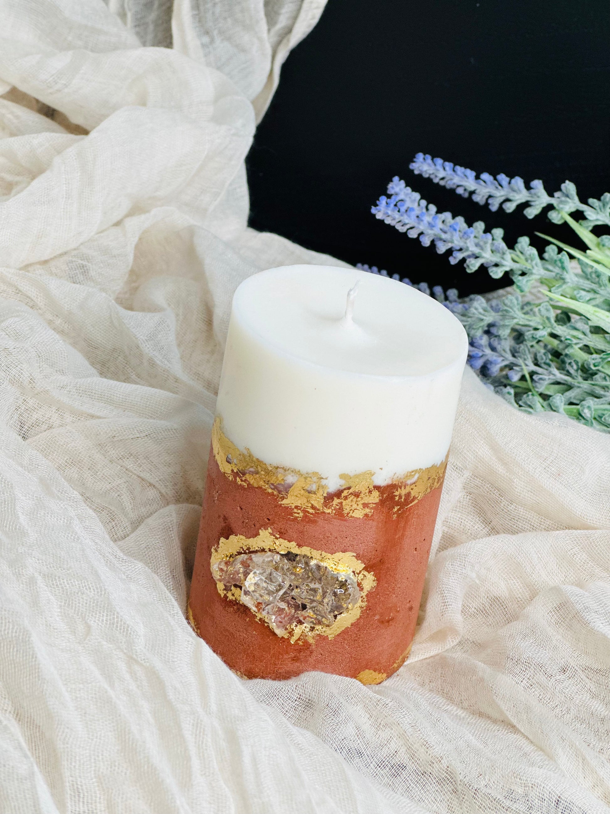 Decorative candle with gold accents on a textured white surface