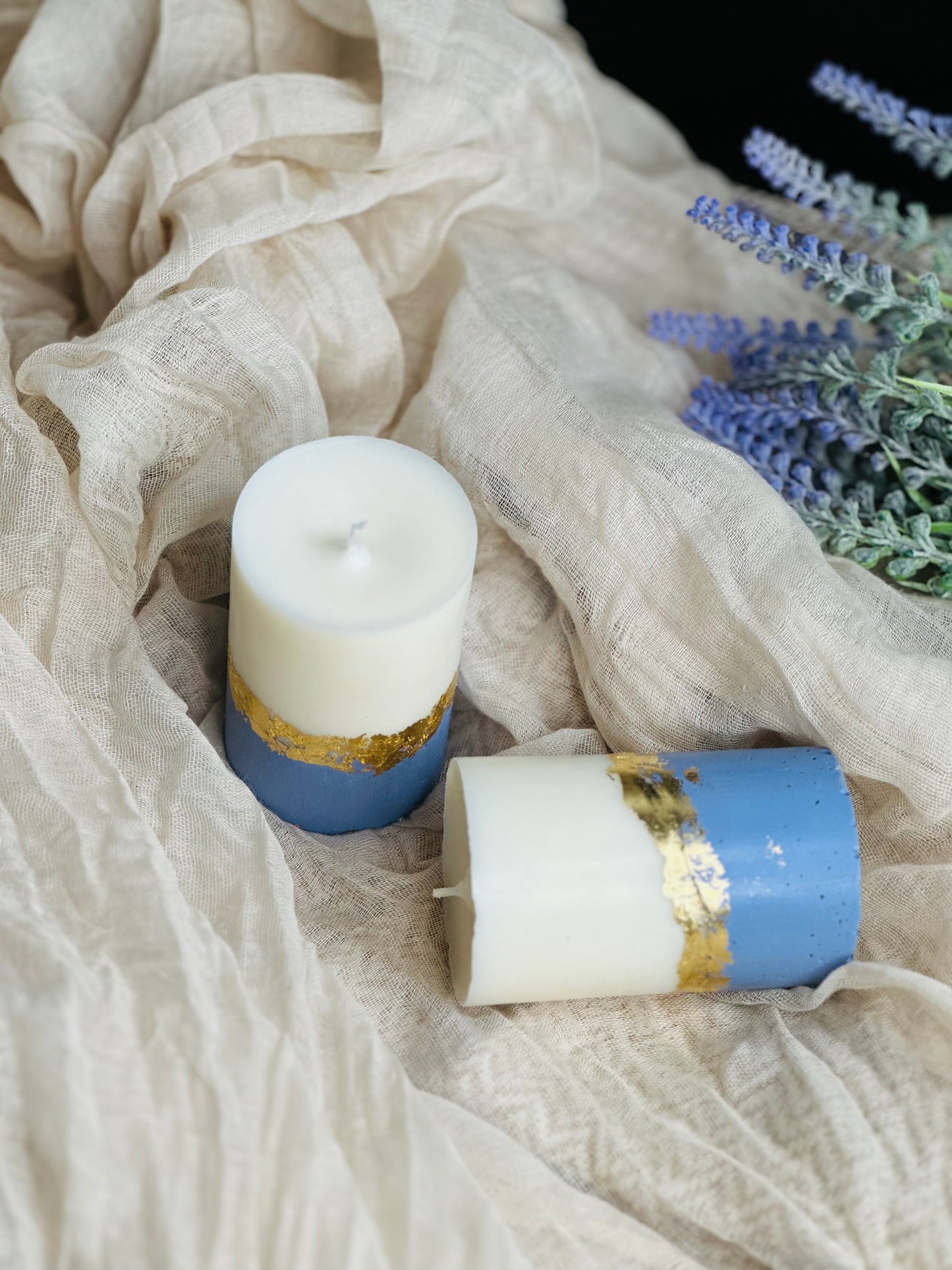 Two candles with gold and blue accents on a textured fabric background - UK made