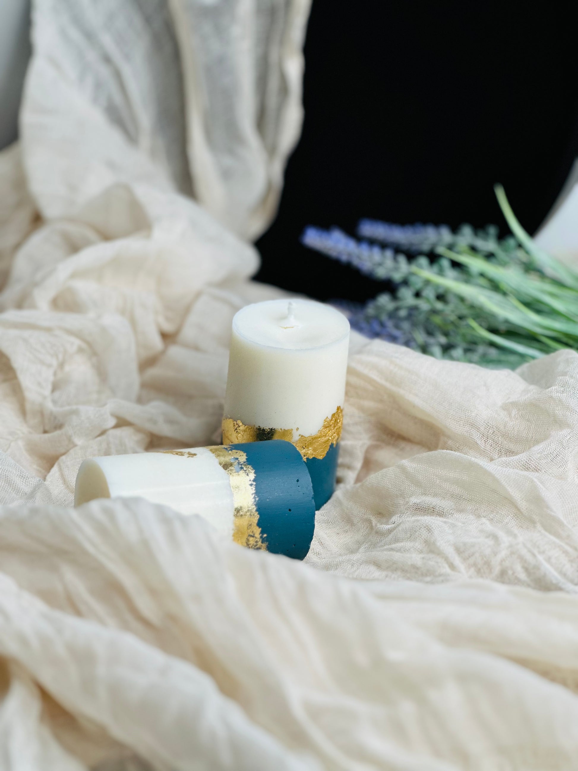 Decorative candle with gold and blue accents on a white fabric background - UK made