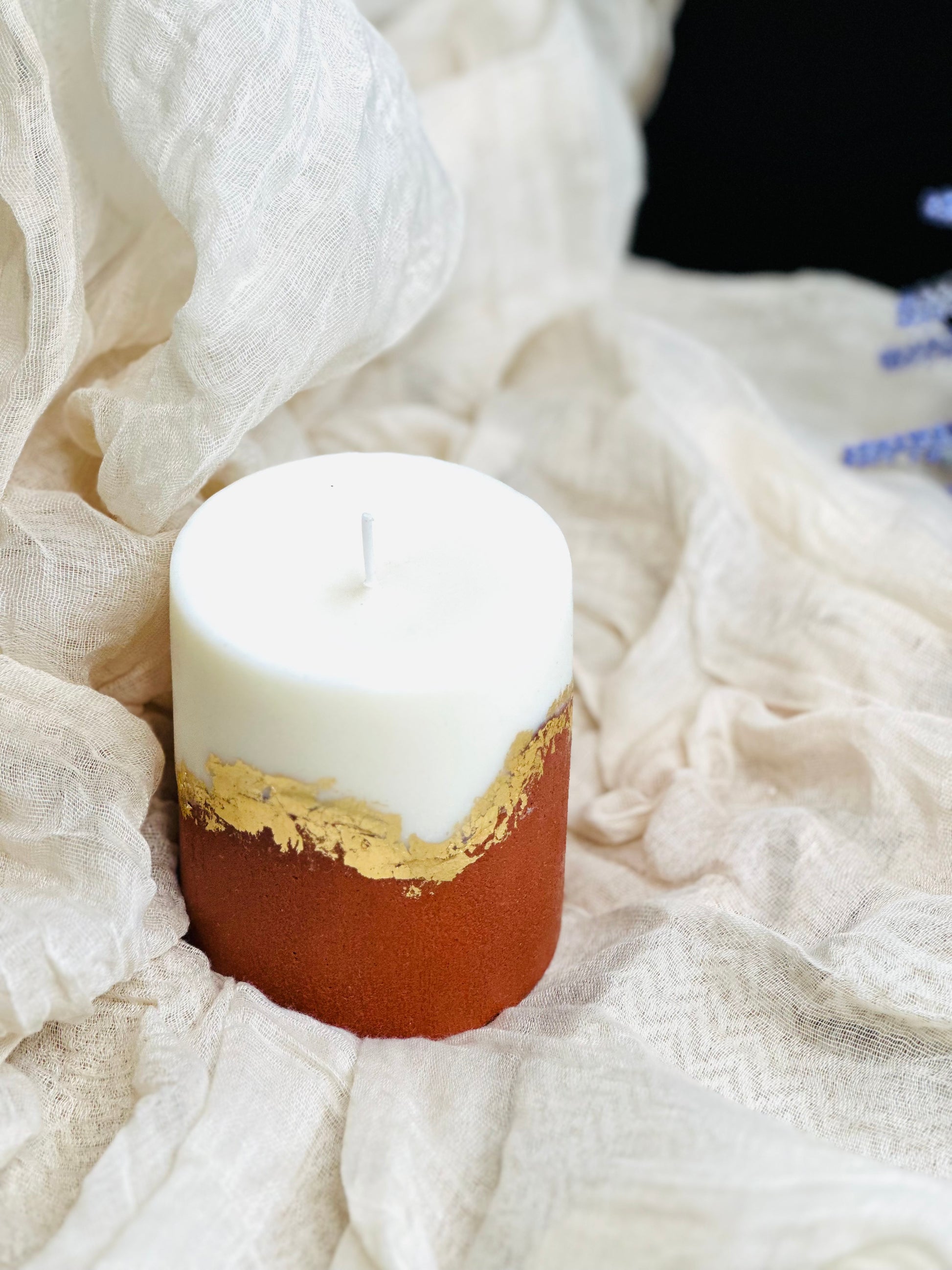 Candle with gold accent on a white fabric background made in UK
